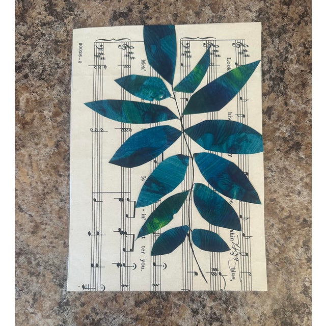 Painted leaves in deep teal and green tones overlay vintage sheet music, creating a graceful fusion of nature and melody....