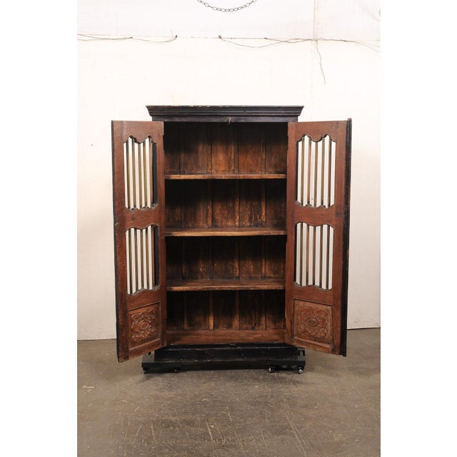 A tall British Colonial two-door storage cabinet from the early 20th century. This antique Anglo-Indian British Colonial...