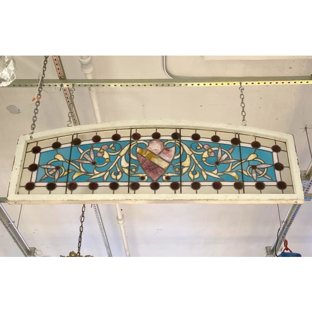 This reclaimed early 1900s window has a shield in the center, with 29 large red jewels near the border. There are red,...