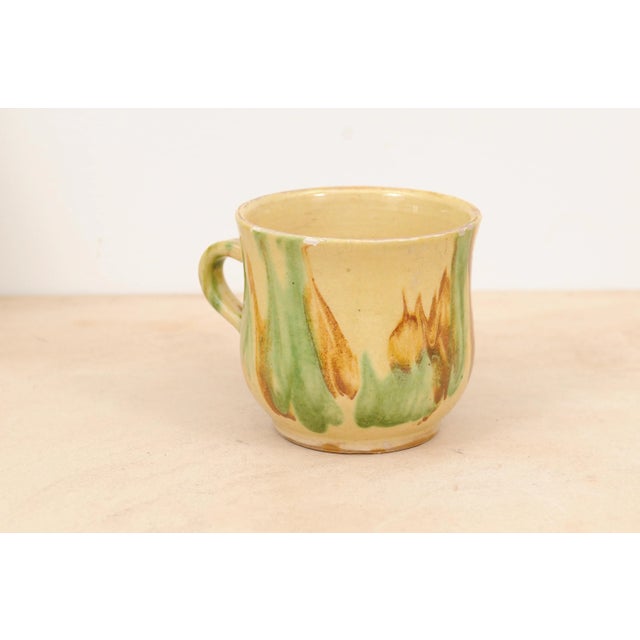 A French pottery mug from the 19th century, with yellow, green and rust glaze. Created in France during the 19th century,...