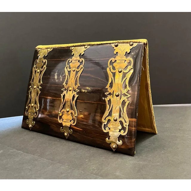 Coromandel wood papers holder. Circa 1850 .Brass embossed straps on the front. cloth backing on the inside and back