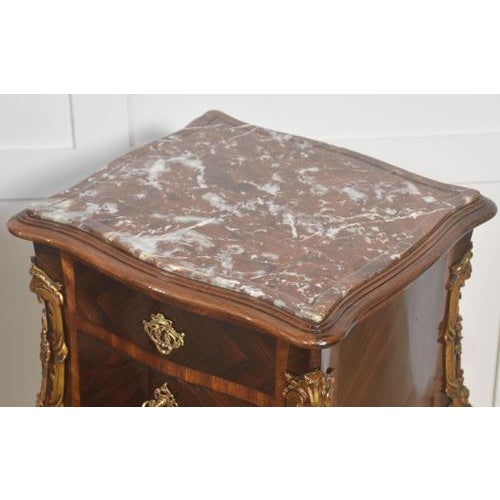 A finely crafted pair of French Louis XV–style bedside cabinets executed in richly figured walnut, each surmounted by a...