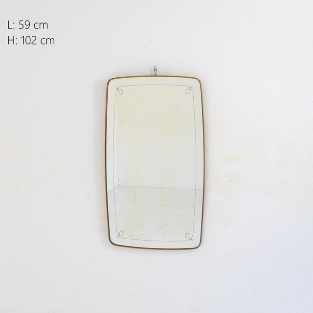 Description Rectangular wall mirror with rounded corners. The frame is thin and made of brass. The mirror surface has a...