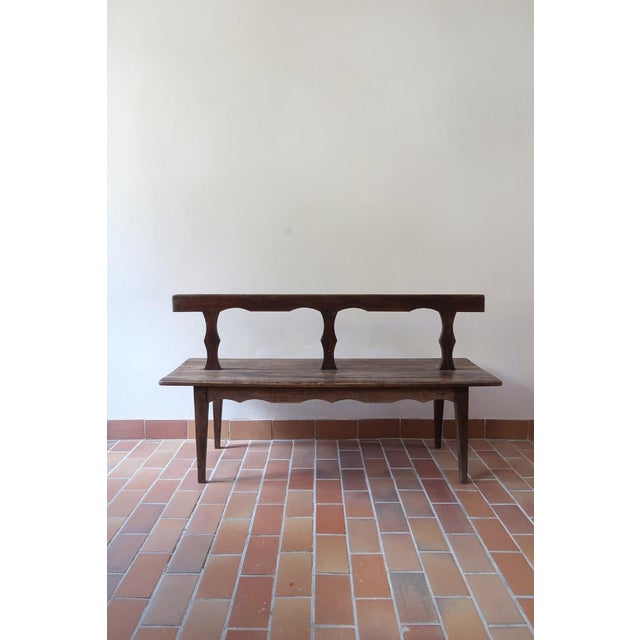 A 19th-century French country bench in solid wood, from the vernacular tradition of rural furniture: made by a village...