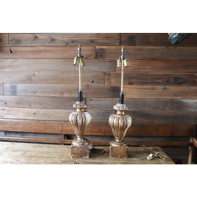 Striking vintage pair of decorative table lamps featuring beautifully carved wooden bases with a gilt finish and elegant...