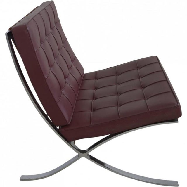Ludwig Mies van der Rohe Barcelona chair upholstered in burgundy colored leather and with a steel frame. The chair is from...