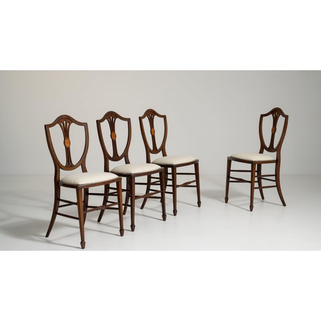 A set of dining chairs in the Hepplewhite style, known for their light construction, shield-back designs, and neoclassical...