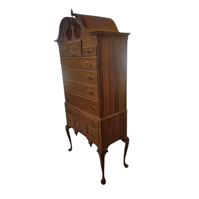 Vintage Queen Anne style highboy chest featuring a dramatic bonnet top, carved shell embellishments, brass hardware, and...
