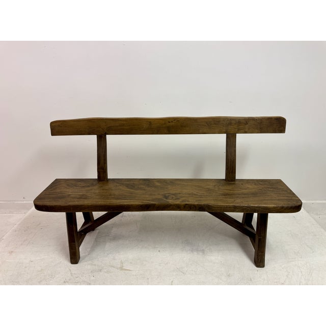 A pair of sculptural elm benches, showcasing a strong, organic approach to form and material. Each bench is crafted from...