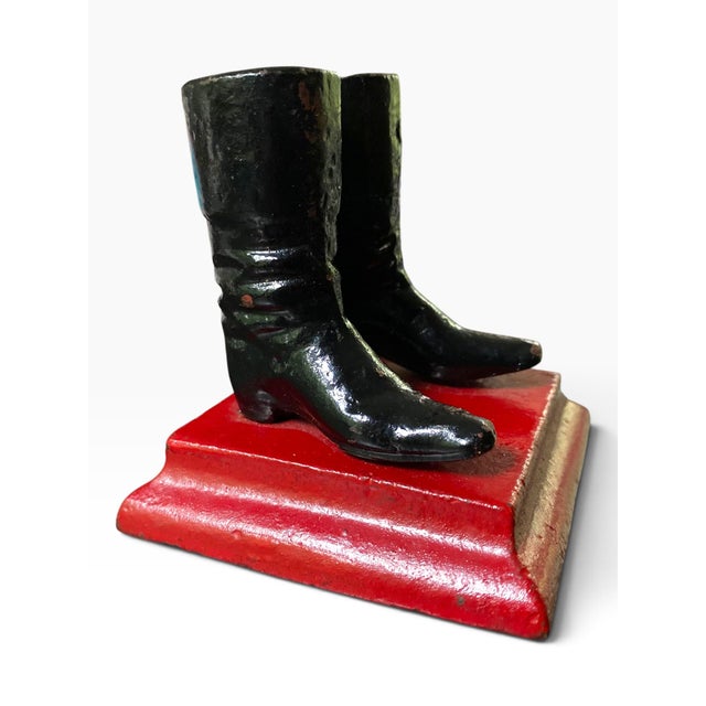 A charming object from England, made of iron and painted with a red base and black boots.