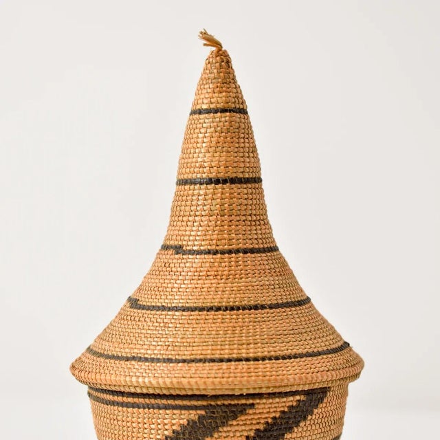 The Tutsi Tight Weave Basket with Lid from Rwanda epitomizes the artistry and tradition of the Tutsi community's weaving...