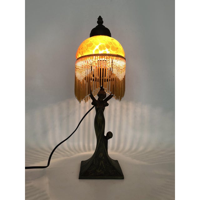 Art Nouveau style table lamp with beaded details and a speckled orange glass globe A beautiful table or bedside lamp with...
