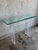 A sleek and timeless mid-century console table featuring a sculptural lucite base topped with thick beveled glass. The...
