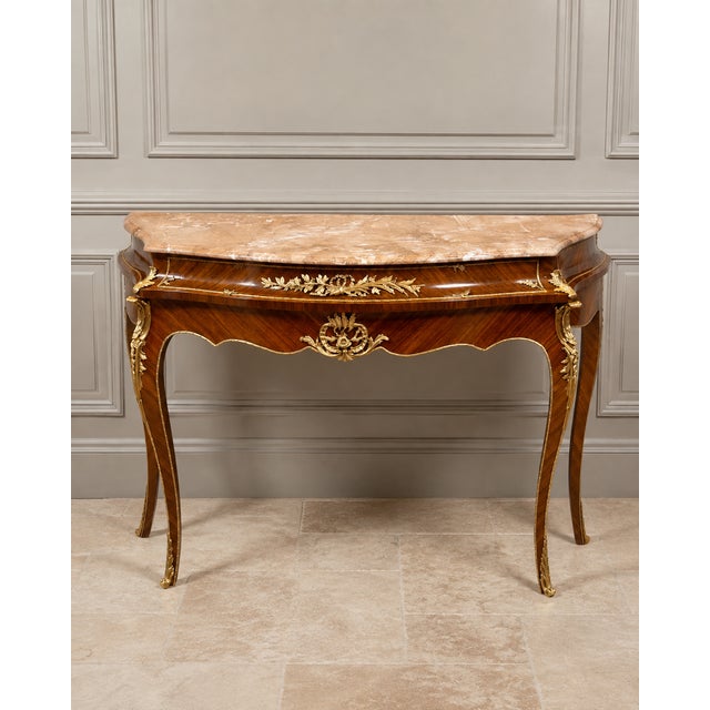 Elegant French Louis XV-style console table featuring a luxurious marble top, richly figured wood construction and...