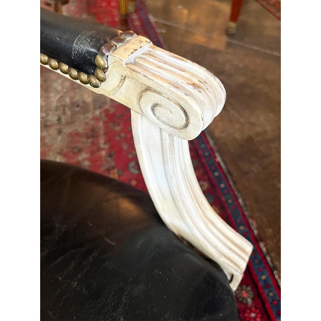 This chair features black leather upholstery on the seat and back cushions. The piece is hand-painted in an off-white...