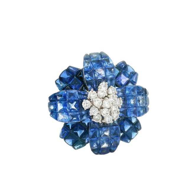 A striking brooch (that can also be worn as a pendant) featuring a captivating array of mixed-cut blue sapphires, weighing...