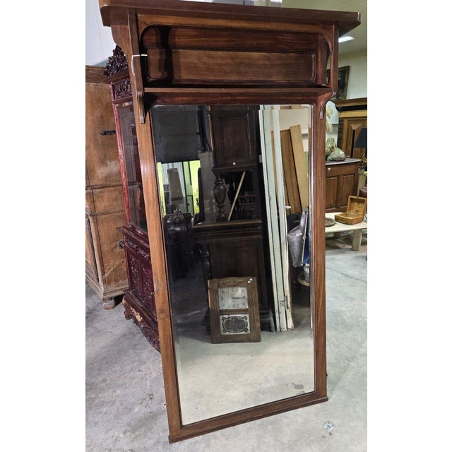 Large Art Nouveau mahogany trumeau mirror with a simple and timeless design. Its brown wood frame features attractive...