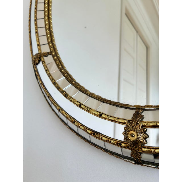 A vintage Spanish Venetian-style oval beveled wall mirror, dating to the 1980s. The mirror has a decorative glass frame...