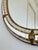 A vintage Spanish Venetian-style oval beveled wall mirror, dating to the 1980s. The mirror has a decorative glass frame...