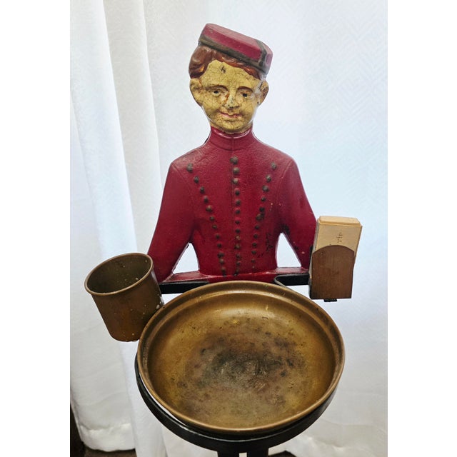 The product is a 1920s or 1930s cast iron "Johnny" Philip Morris bellboy advertising smoking stand. This ashtray stand,...