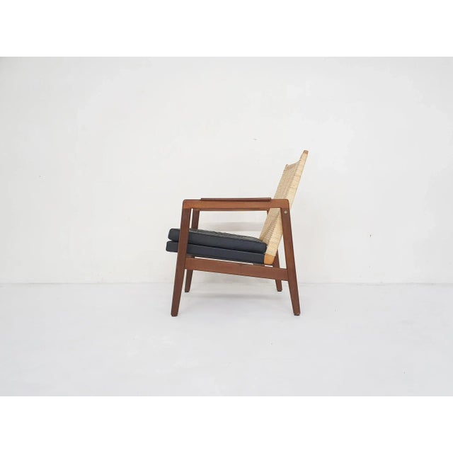 Elegant lounge chair with woven back and black leather cushion. The back has new rattan and we made a new cushion with...