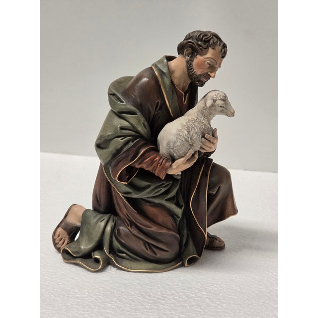 This Italian Baroque nativity sculpture represents a kneeling shepherd holding a small lamb close to his chest. The...