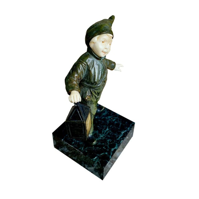 A fine Art Deco period bronze depicting a young Dutch boy holding a lantern. His face and hands are carved bone and he...