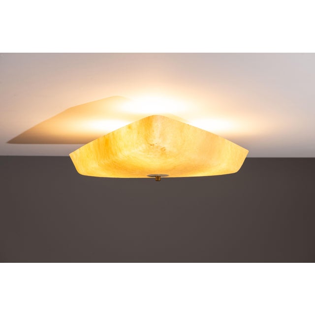This elegant ceiling lamp features a distinctive triangular design that immediately draws the eye. Its shade, crafted from...