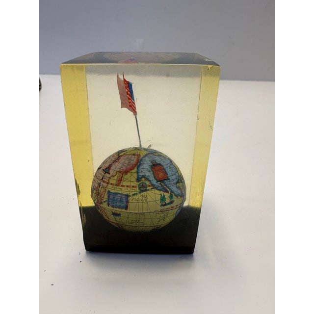 A charming mid-century lucite paperweight featuring a detailed miniature globe crowned with an American flag, fully...