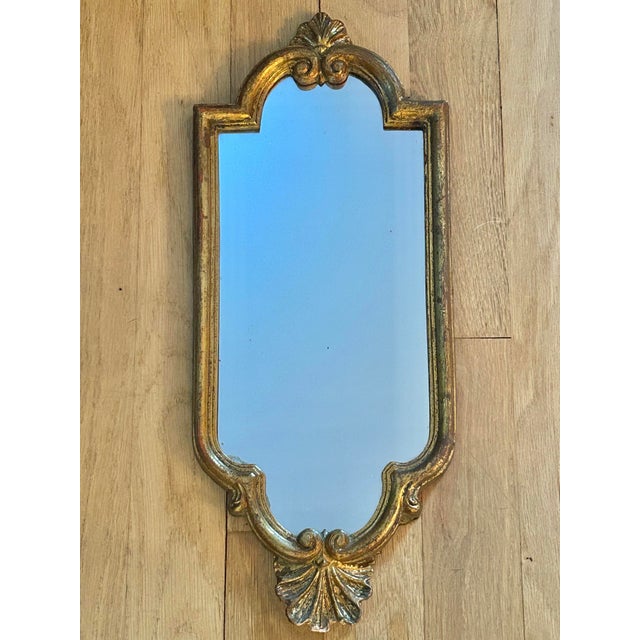 This Florentine wall mirror was handcrafted in Italy and dates to approximately the mid-20th century. The slender giltwood...