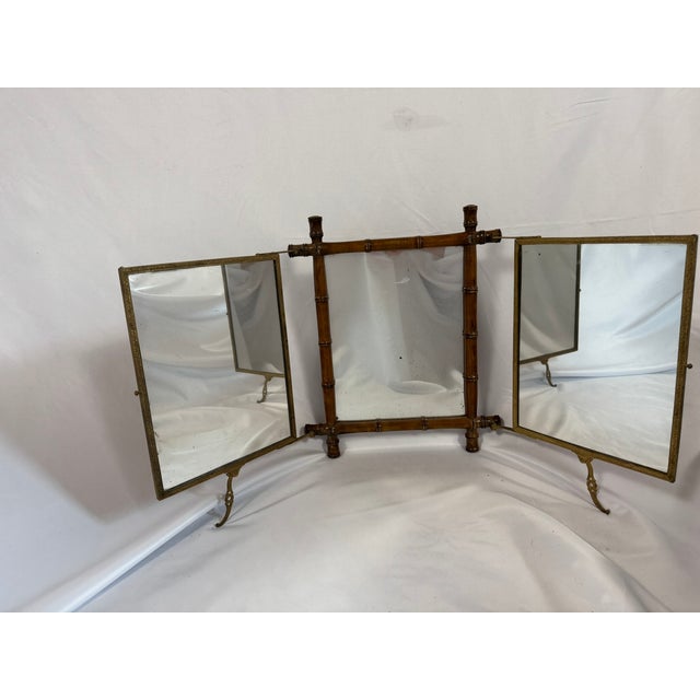 This is an antique triptych dressing mirror in the Aesthetic Movement taste, with a faux-bamboo styled bronze frame and...