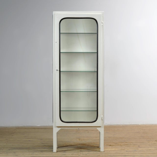 Vintage medical cabinet from the 1970s, made in Hungary. The cabinet is made of iron and glass, with the glass clamped to...