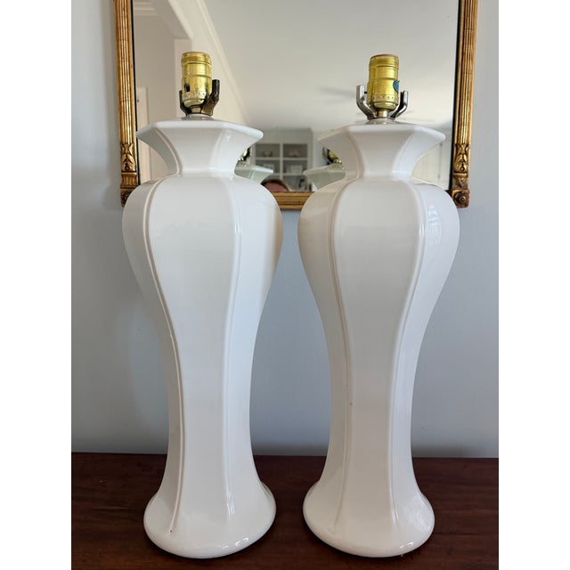 Pair of Hollywood Regency white ceramic lamps in nice vintage condition. Tall with a great shape.
