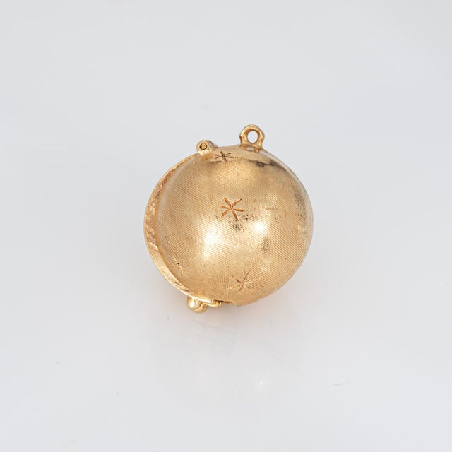 Finely detailed vintage folding picture charm (circa 1960s) crafted in 14 karat yellow gold. The orb features three...