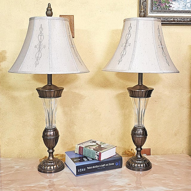 Elegant matched pair of vintage lead crystal table lamps featuring tall fluted crystal columns, urn-form metal accents and...