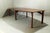 Large teak table; the legs are made of solid teak, and the tabletop is teak-veneered. The leg mounts have been...