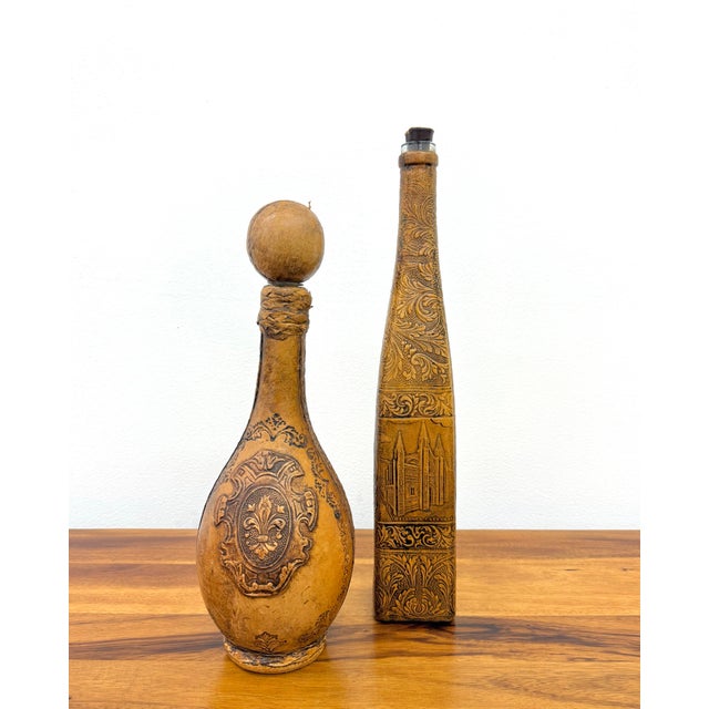A charming pair of vintage Spanish leather-wrapped decorative bottles featuring richly embossed floral scrollwork,...