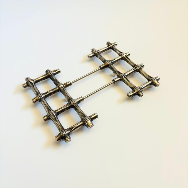 A vintage expanding trivet made out of silver toned metal with a bamboo design. Measures 7" Square x 1"H and expands to...