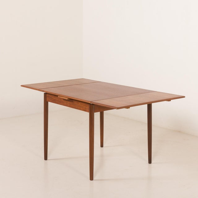 Danish vintage mid-century square teak extension table. It features two additional pull-out leaves that hide under the...