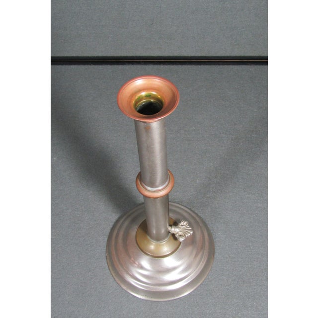 A handsome antique “push-up” candlestick in mixed metals—warm brass and copper highlights set against a silver-tone column...