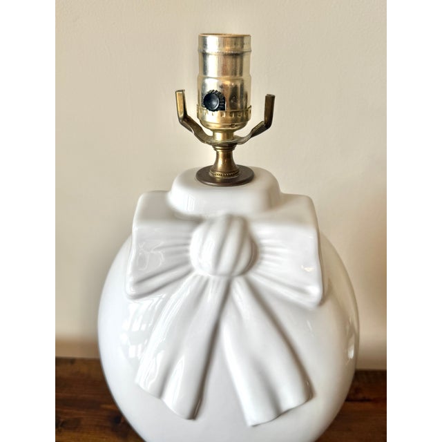 Delightful glossy white porcelain lamp with large bow in relief, circa 1980s. Most items found at Pub & Oasis are vintage...