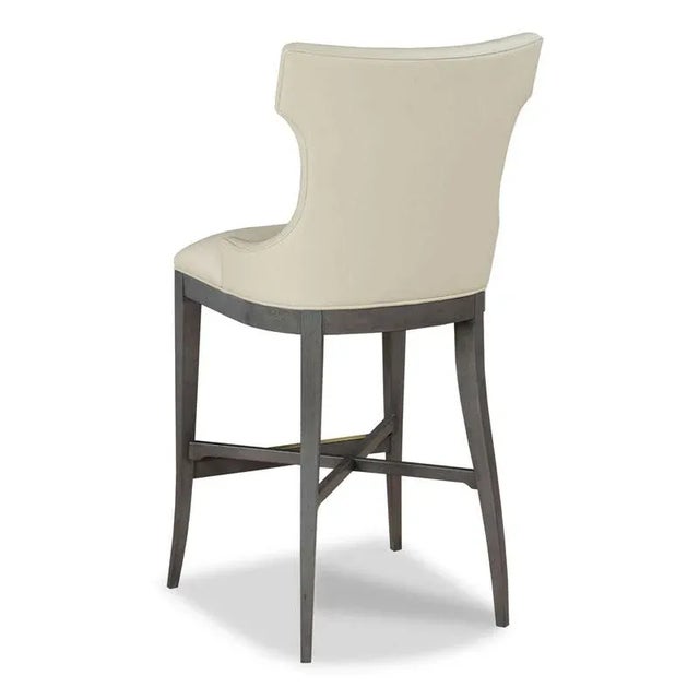 A curved upholstered back wraps around an upholstered seat with welt trim raised by graceful tapering flared legs. The...