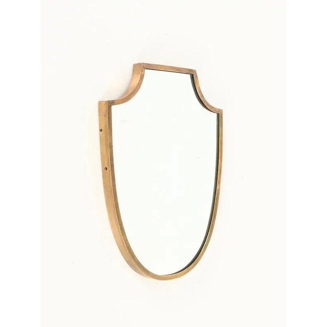 Stunning small shield-shaped mirror with a solid brass frame. This incredibly elegant piece was produced in Italy during...