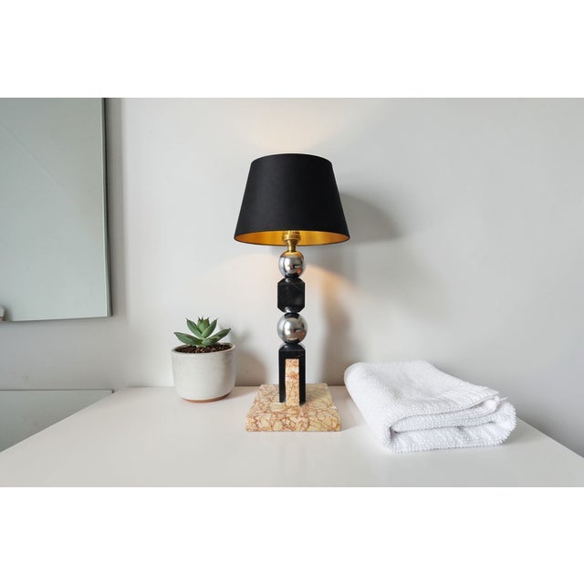 A stunning table lamp with a design attributed to jacques adnet, elegantly blending veined marble and chrome elements,...
