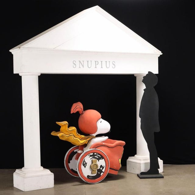 Set depicting Snoopy driving a chariot and a large temple with the writing 'SNUPIUS'. This piece is attributed to the...