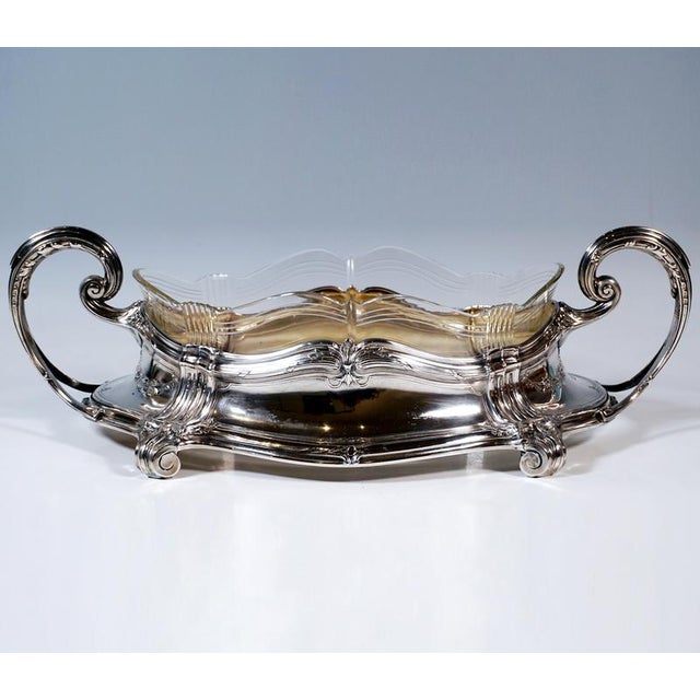 Elegant silver vessel in an oval shape with a protruding base, four moulded bands as pilasters extending into volute feet,...