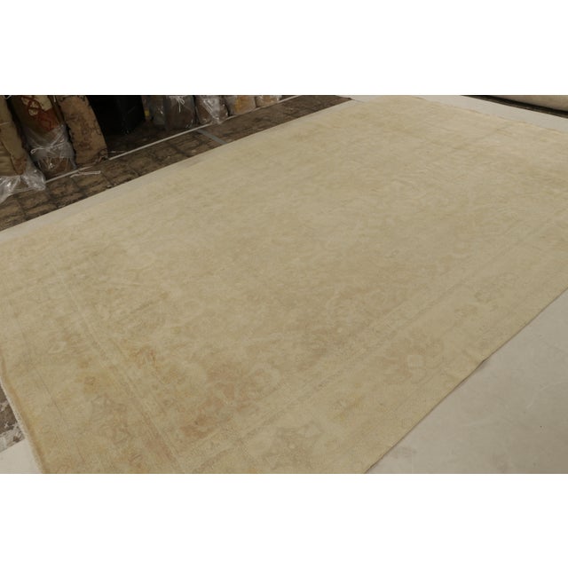 Hand Knotted in wool, this 9x13 antique Oushak rug has all over subdued floral patterns in gold and beige-brown accents....