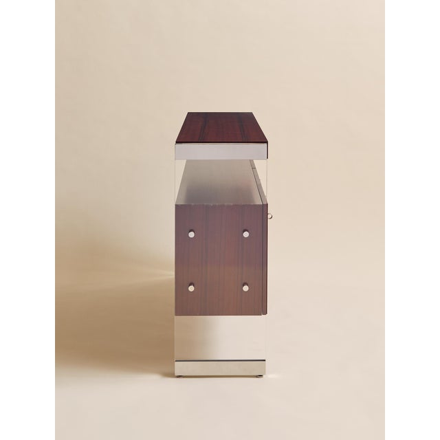 A sculptural mix of warm wood and clear lucite, this console pairs clean-lined cabinetry with airy, architectural sides....