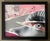 This artwork features a striking close-up of a human eye, partially obscured by a jagged tear that reveals a vibrant pink...