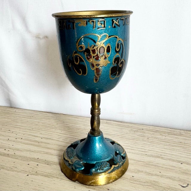 This vintage Israeli Kiddush cup is crafted in brass and finished with a rich blue enamel, accented by hand-painted...